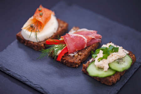 Delicious little sandwiches with tuna, cheese, prosciutto and vegetables.の写真素材