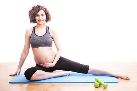 young pregnant woman exercises on the mat. Isolated shotの写真素材