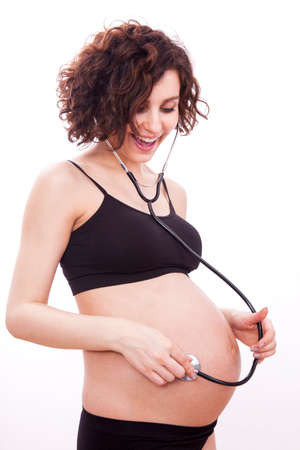 Pregnant woman listens to her child through a stethoscope.の写真素材