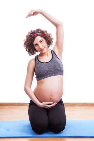 young pregnant woman exercises on the mat. Isolated shotの写真素材