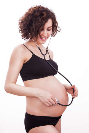 Pregnant woman listens to her child through a stethoscope.の写真素材