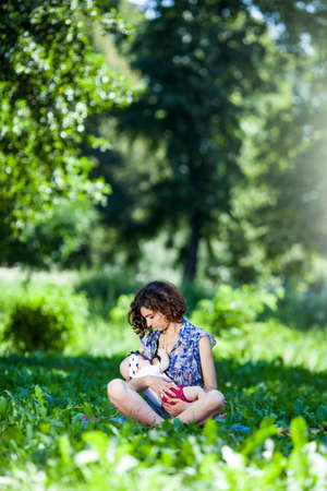 Young beautiful mother sits on blanket with her daughter during a picnic in the parkの写真素材