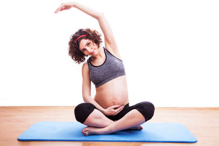 young pregnant woman exercises on the mat. Isolated shotの写真素材