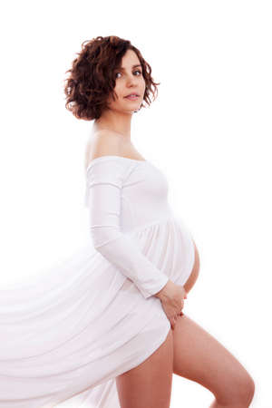 Pregnant woman in white dress on white background.の写真素材