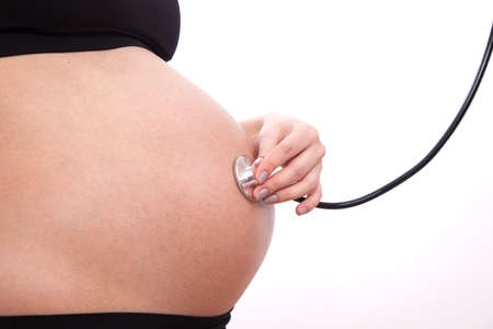 Pregnant woman listens to her child through a stethoscope.の写真素材