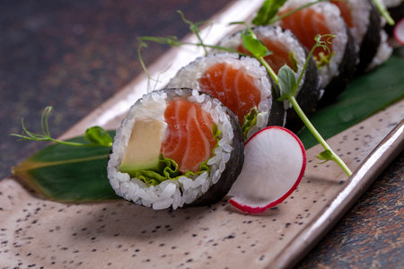 Sushi roll with salmon, avocado, cucumber and red radishの写真素材