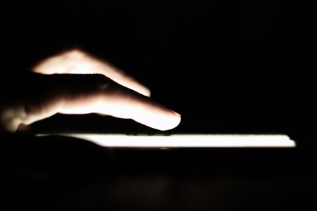 hand touching screen on modern digital tablet pc in a dark roomの写真素材