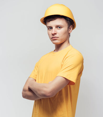 Worker in yellow helmet standing with arms crossed