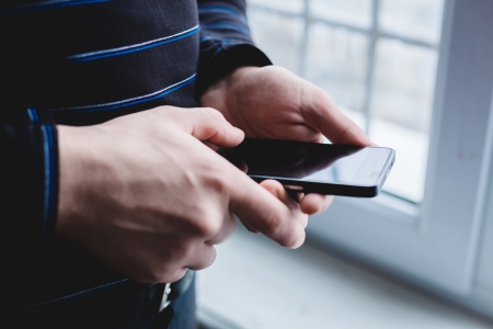 The man is using a smartphone. Modern mobile phone in hand.