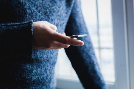 The man is using a smartphone. Modern mobile phone in hand.