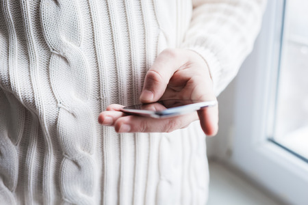 The man is using a smartphone. Modern mobile phone in hand.
