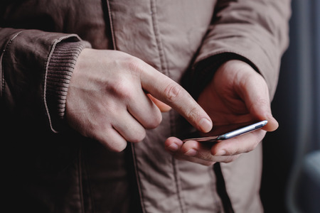 The man is using a smartphone. Modern mobile phone in hand.