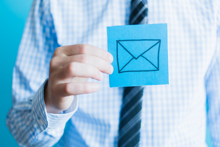 man's hand holding closed envelope againstの写真素材