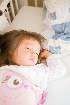 Adorable little girl sleep in the bedの写真素材