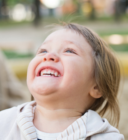 cute little girl smiling in a park close-upの写真素材