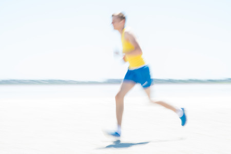Young male runner running on a empty beach at dawn. Blur effect.の写真素材