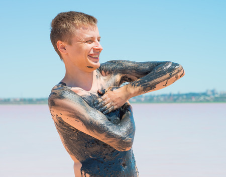 men is applying mud on the beachの写真素材