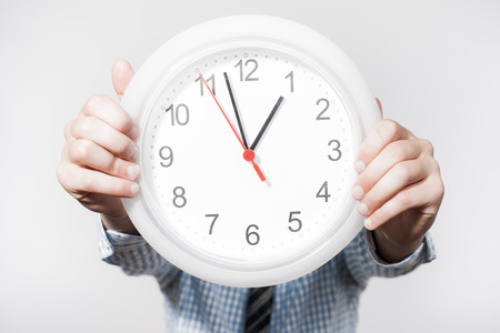 Discontented  businessman holding wall clock.の写真素材