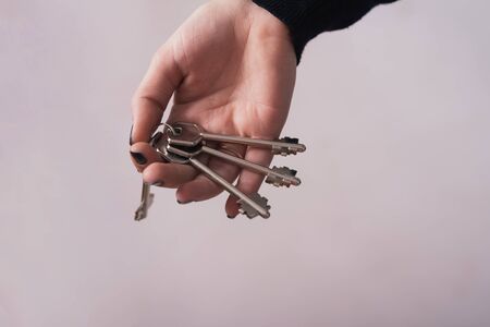 Woman hand holding keys on Gray backgroundの写真素材