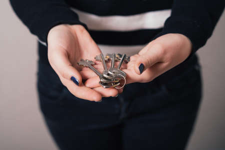 Woman hand holding keys on Gray backgroundの写真素材