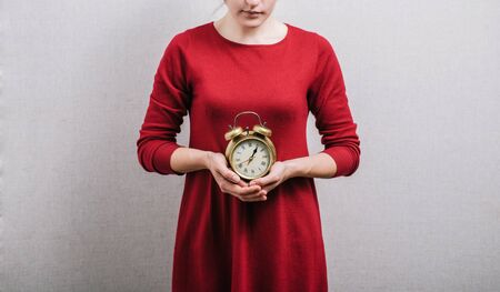 Woman hands holding an alarm clock On a gray background.の写真素材