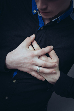 Man hands on his chest, a sore heart. Gesture heart aches attack. On a gray backgroundの写真素材