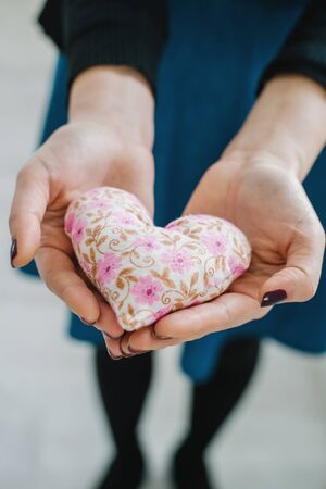 Picture of a small white heart in hands, female holds handmade sewn soft toy, woman with Valentine...