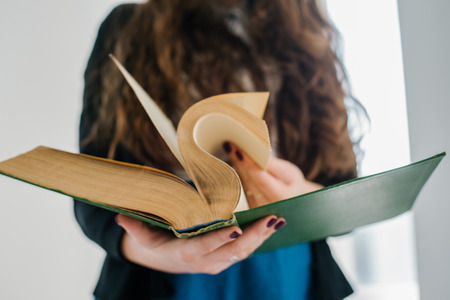 female hands Leafs big old book close upの写真素材