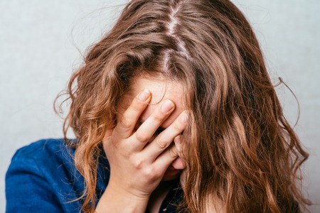 Close-up portrait of surprised attractive businesswoman covering her mouth by the hands, over white backgroundの写真素材