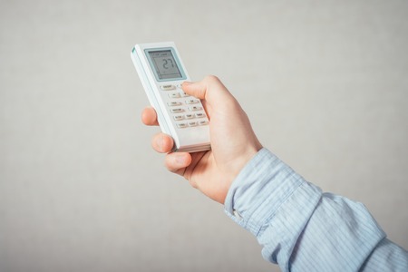 Hand with remote control directed on the conditioner