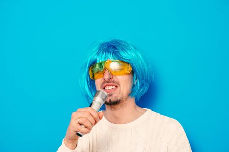 A man in a wig, and sunglasses singing into a microphone.の写真素材