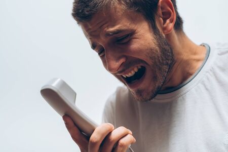 Close up image of a man screaming on the telephone during the conversation.
