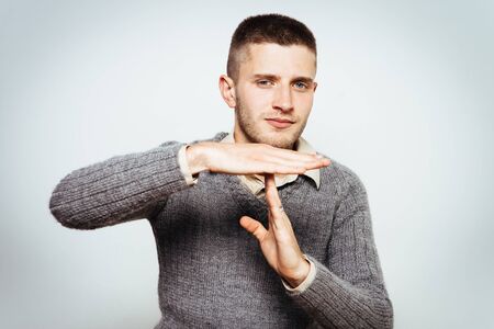 A man shows the hands stop timeout. On a gray background.