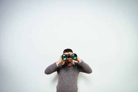 man with binoculars. gray backgroundの写真素材