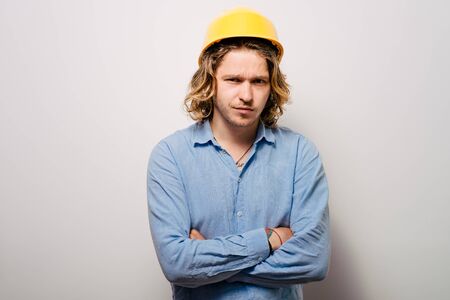 Handsome young man with protective helmet on his head and arms crossedの写真素材