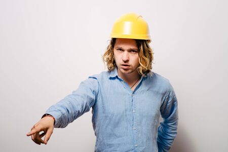 Frowning manual worker - builder, pointing with finger to you or camera, isolated on gray background, close-up studio shot.の写真素材