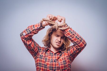 Tortured business man holding his hands tied with a rope