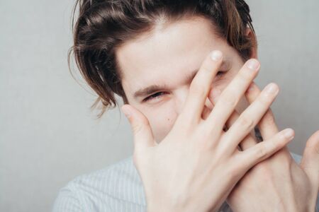 Portrait of a handsome man covering his eyes with hand in studioの写真素材