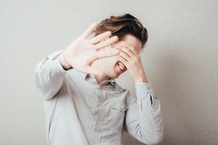 Portrait of a handsome man covering his eyes with hand in studioの写真素材