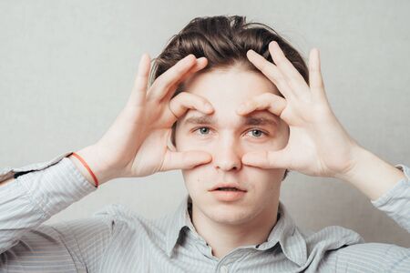 young man showing binocularsの写真素材