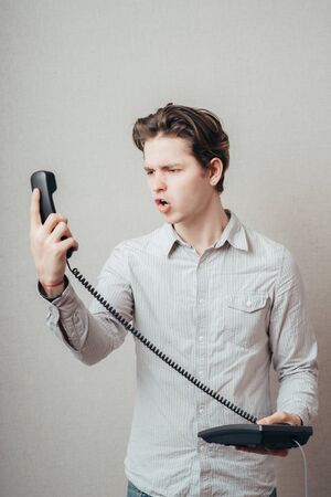 portrait of young man talking on a vintage telephoneの写真素材