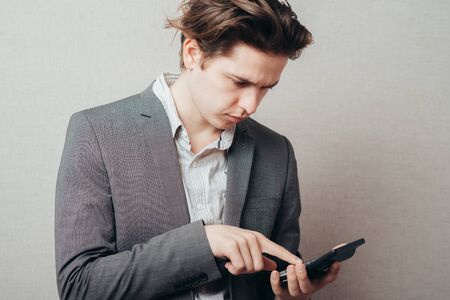 Thinking young man with calculator on greyの写真素材