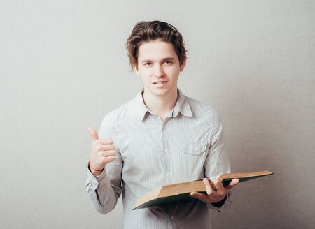 Portrait of young man  reading isolated over grey background