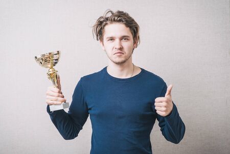 young man holding a prize cup and happy