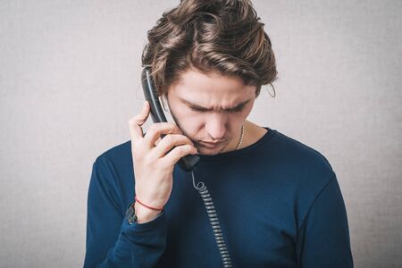 Young man with office or home phone. On a gray background.