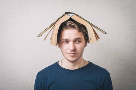 Bored college student with a book on his headの写真素材