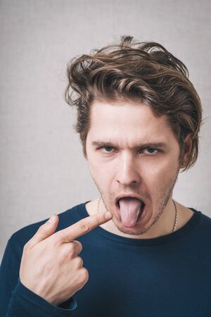 young man with finger on tongueの写真素材