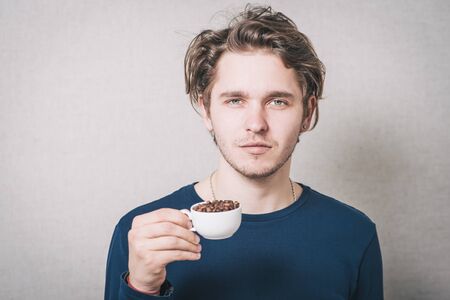 Man with a cup of coffee beans. Gray backgroundの写真素材
