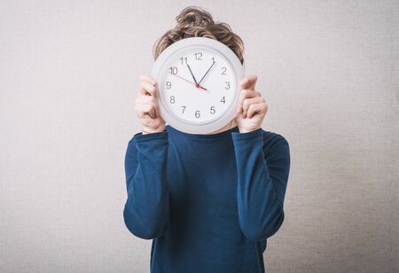 young man holding a big clock.