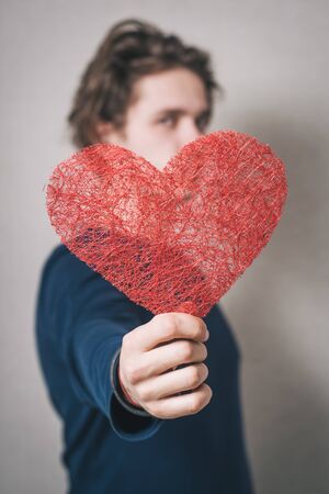 A man with a red heart. Gray background.